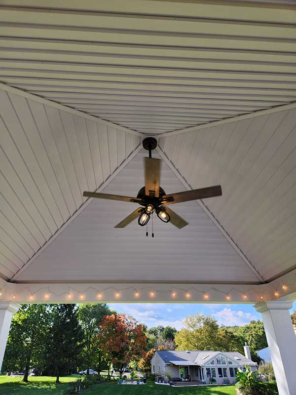 Ceiling fan installation under a porch roof with decorative lighting, showcasing a residential outdoor space by Nalset Electrical Services.