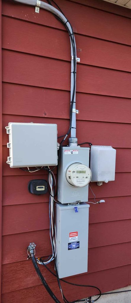Disconnect box installation on exterior wall with electrical meter and conduit, showcasing Nalset Electrical Services' expertise in residential electrical upgrades.