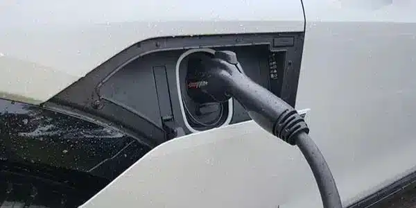 Electric vehicle charging connector plugged into a white vehicle, illustrating EV charger installation services by Nalset Electrical Services for homeowners in Chalfont.