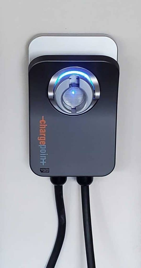 EV charger installation featuring ChargePoint unit with illuminated indicator light and charging cables.