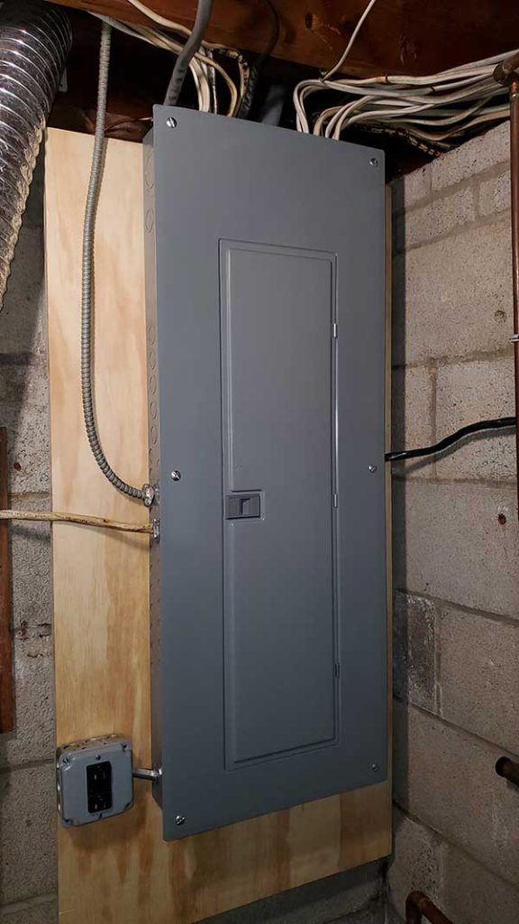 Main electrical panel installation mounted on plywood, showcasing electrical wiring and connections in a residential setting.