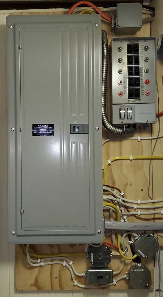 Main electrical panel installation by Nalset Electrical Services, featuring a gray panel with circuit breakers and wiring on a wooden background.