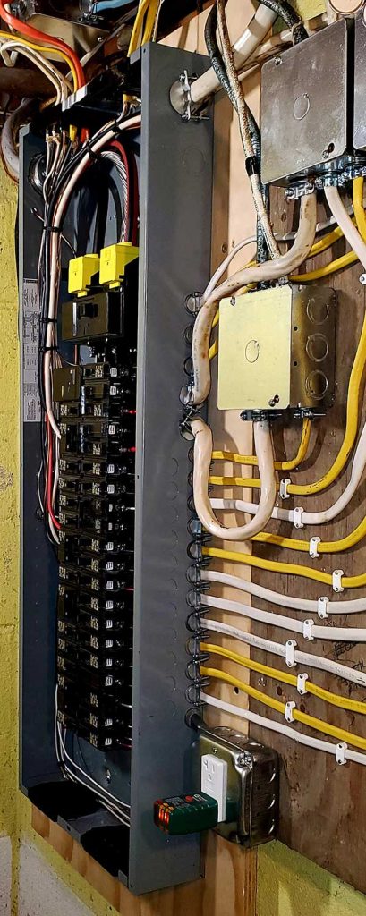 Main electrical panel installation with circuit breakers, wiring, and electrical boxes on a wall.