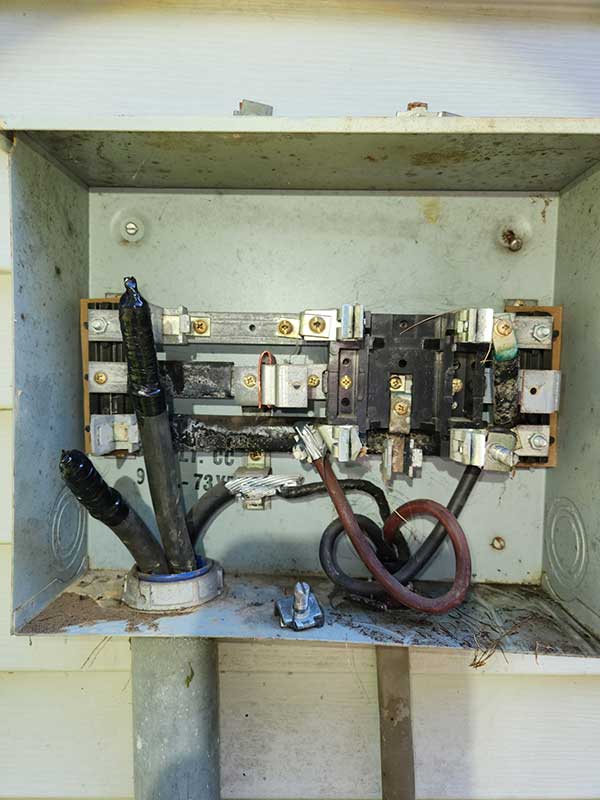 Electrical meter base with exposed wires and connections, highlighting potential safety hazards and the need for electrical inspection services.