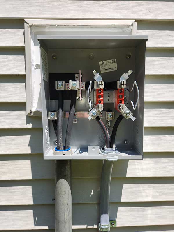Meter base installation showing electrical connections, wires, and components mounted on a wall, highlighting Nalset Electrical Services' expertise in electrical installations.