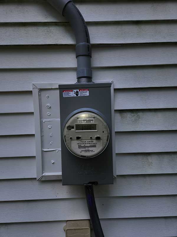 Meter base installation on exterior wall with electrical meter and conduit, showcasing residential electrical service upgrade by Nalset Electrical Services.