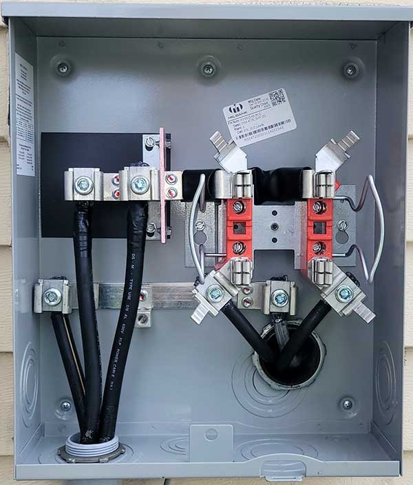Meter base installation showcasing electrical connections, including cables and terminal blocks, within a metallic enclosure.