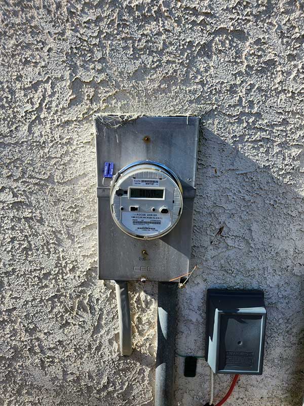 Electrical meter installation on textured wall, showcasing safety compliance and readiness for emergency electrical services.