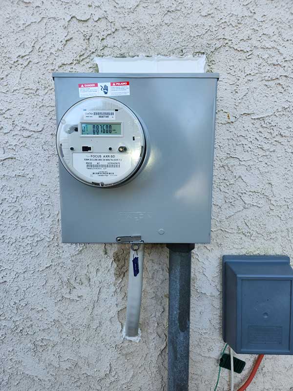 Meter base installation on exterior wall with digital meter and disconnect box, showcasing electrical service upgrade by Nalset Electrical Services.
