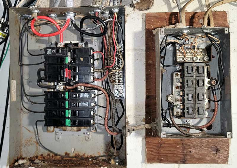 Electrical panel with exposed wiring and circuit breakers, highlighting unsafe electrical conditions relevant to electrical safety inspections and emergency repairs.