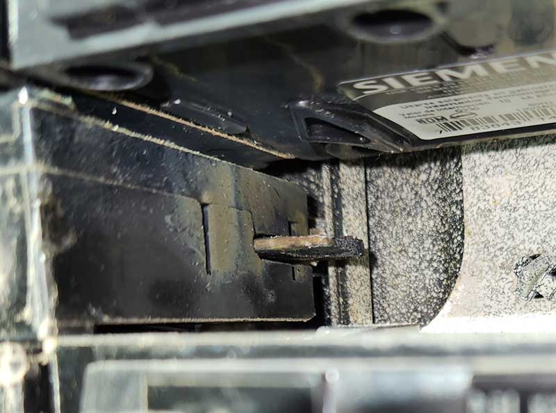 Close-up of an unsafe electrical panel showing a damaged breaker and signs of wear, highlighting electrical safety concerns.