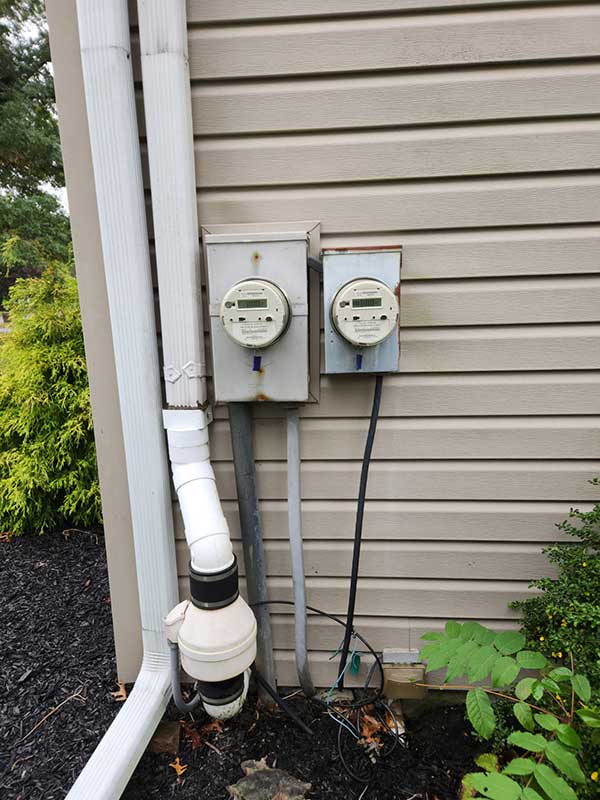 Electrical meters installed on a residential building, showcasing potential unsafe electrical conditions, emphasizing the importance of electrical safety inspections and emergency repairs.